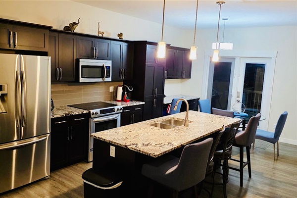 Modern kitchen w/ granite island, stainless appliances, dining nook.