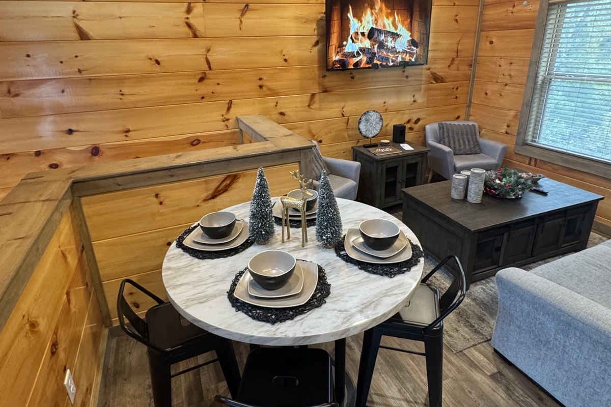 Woke up to this cozy cabin with golden wood walls glowing softly, a crackling fire on the screen, and a marble table beautifully set for four. Morning light streamed through the window with rustic charm, the perfect start to a peaceful day in the woods.