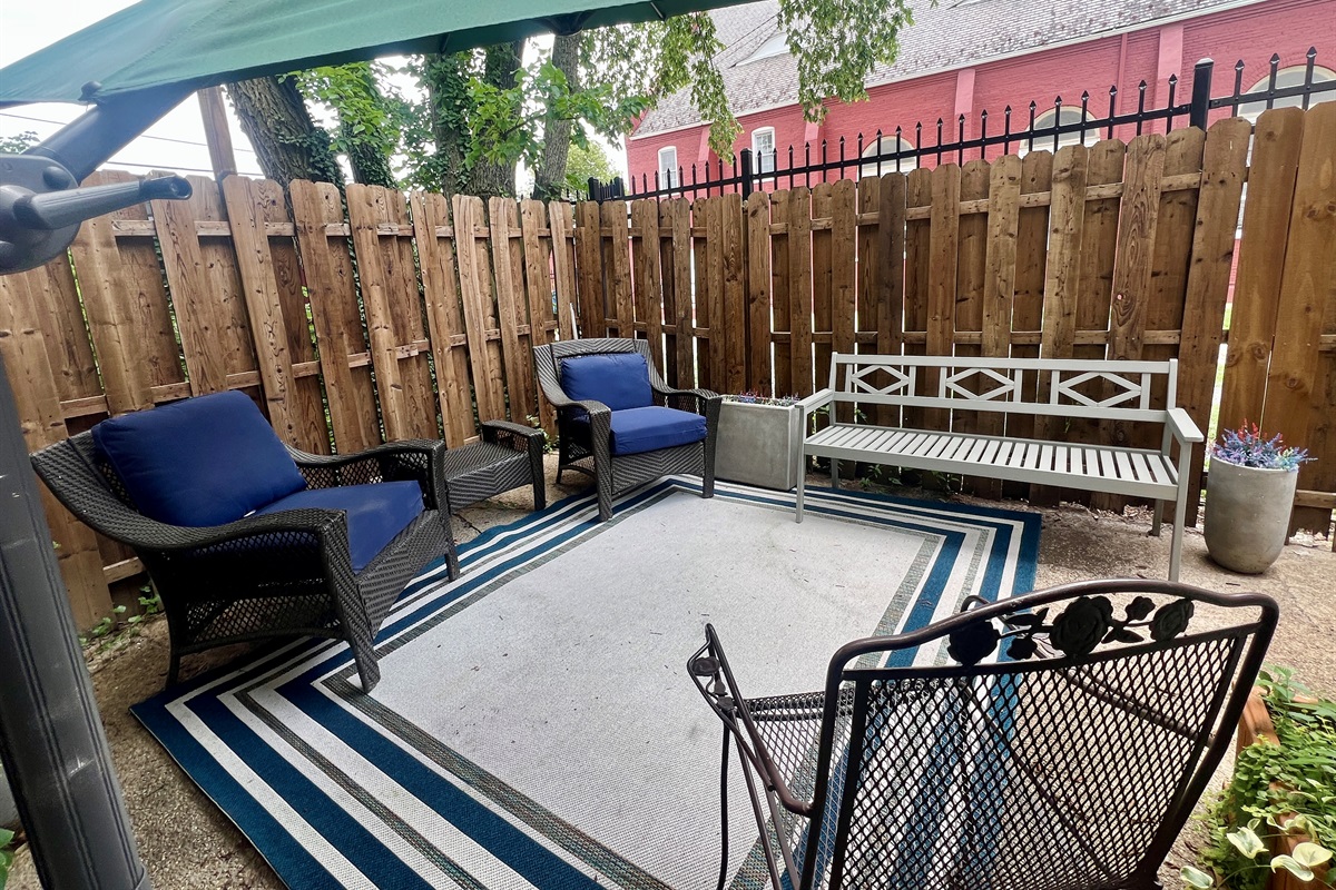Cozy fenced-in patio with comfortable seating, outdoor rug, and a charming view of the church next door