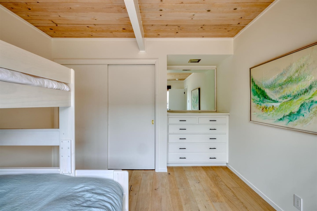 - Spacious bunk room with built in dresser and plenty of closet storage  
- Light wood flooring and minimal decor for a clean, uncluttered vibe  
- Large mirror reflects light, making the room feel open and airy  
