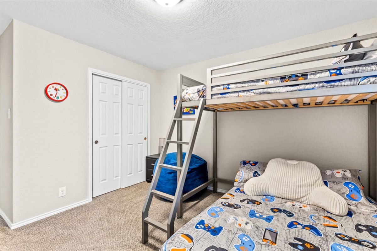 Kid-approved bedroom with bunk bed setup, children’s books, toys, baby safety gate access, and soft linens.