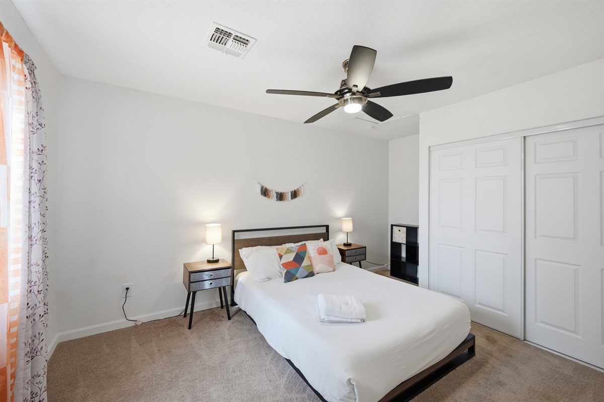 This stylish bedroom blends modern decor with warm, earthy tones, offering a restful space complete with cozy textures and thoughtful touches.