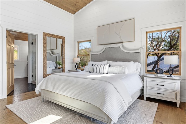 This bright, spacious bedroom features an upholstered headboard, soft-close nightstands, luxurious wool rug, generous walk-in closet with shelving, and a private bath with walk in shower and soaking tub that add to the spa-like serene feel.