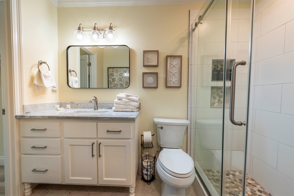 Bright coastal bathroom with modern shower, fresh towels, and relaxing vibes.
