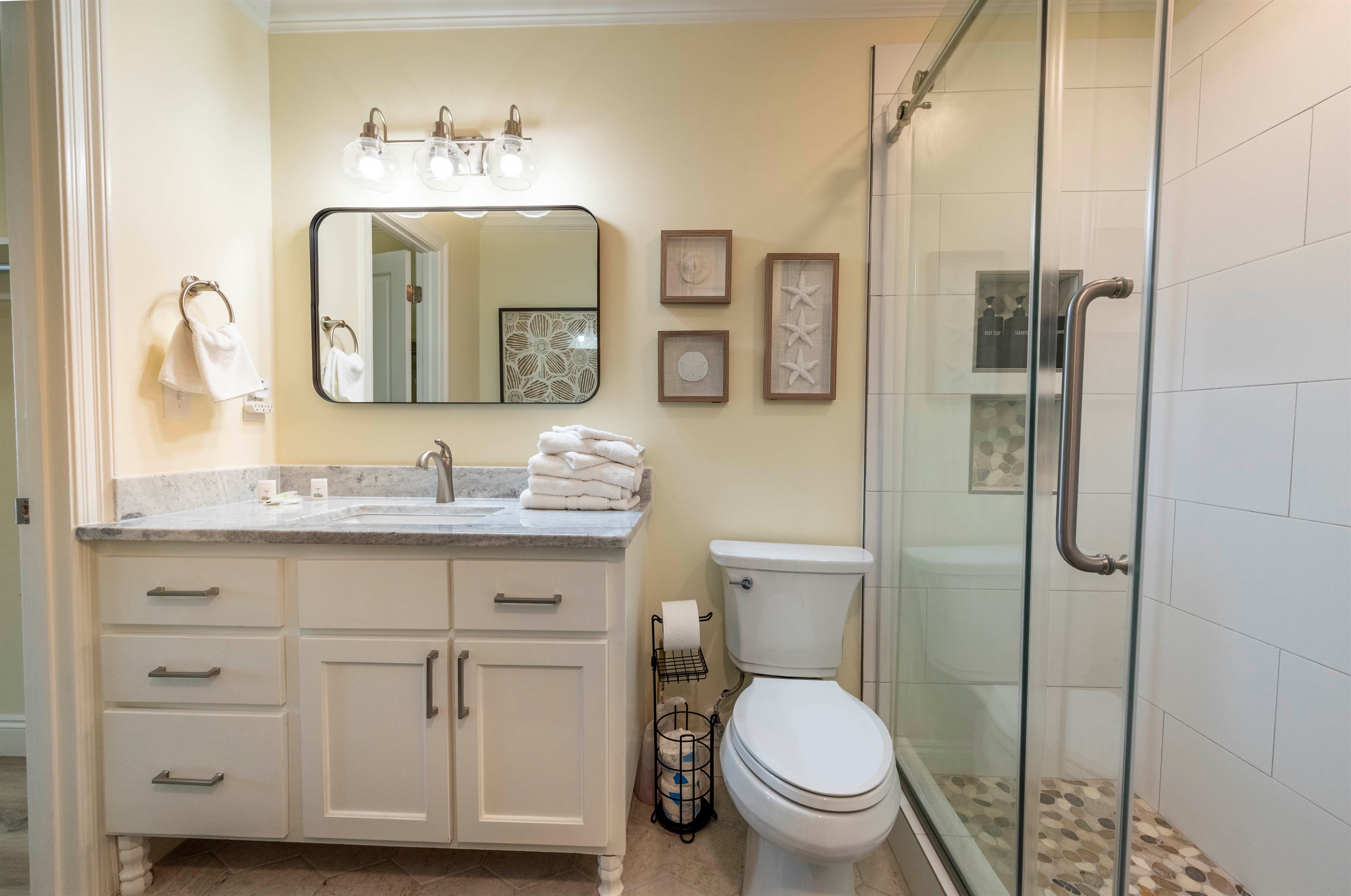Bright coastal bathroom with modern shower, fresh towels, and relaxing vibes.