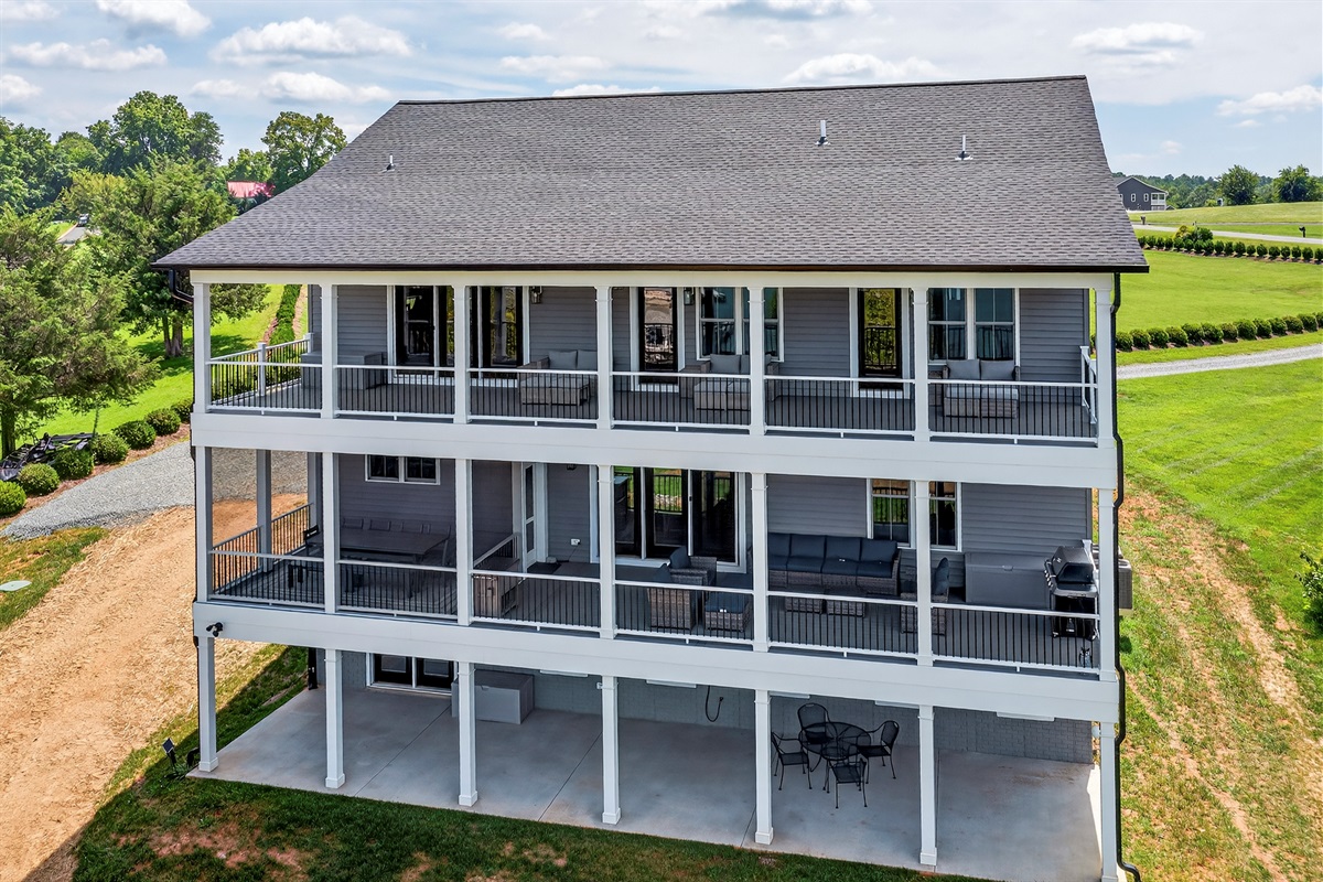 Stunning three-level lakefront home with expansive wraparound decks on both upper floors, offering multiple outdoor living spaces to soak in panoramic views of the water.