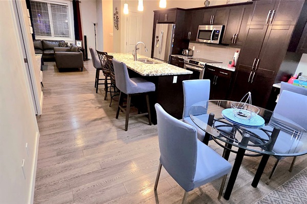 Sleek open kitchen with island seating, stainless appliances, chic dining.