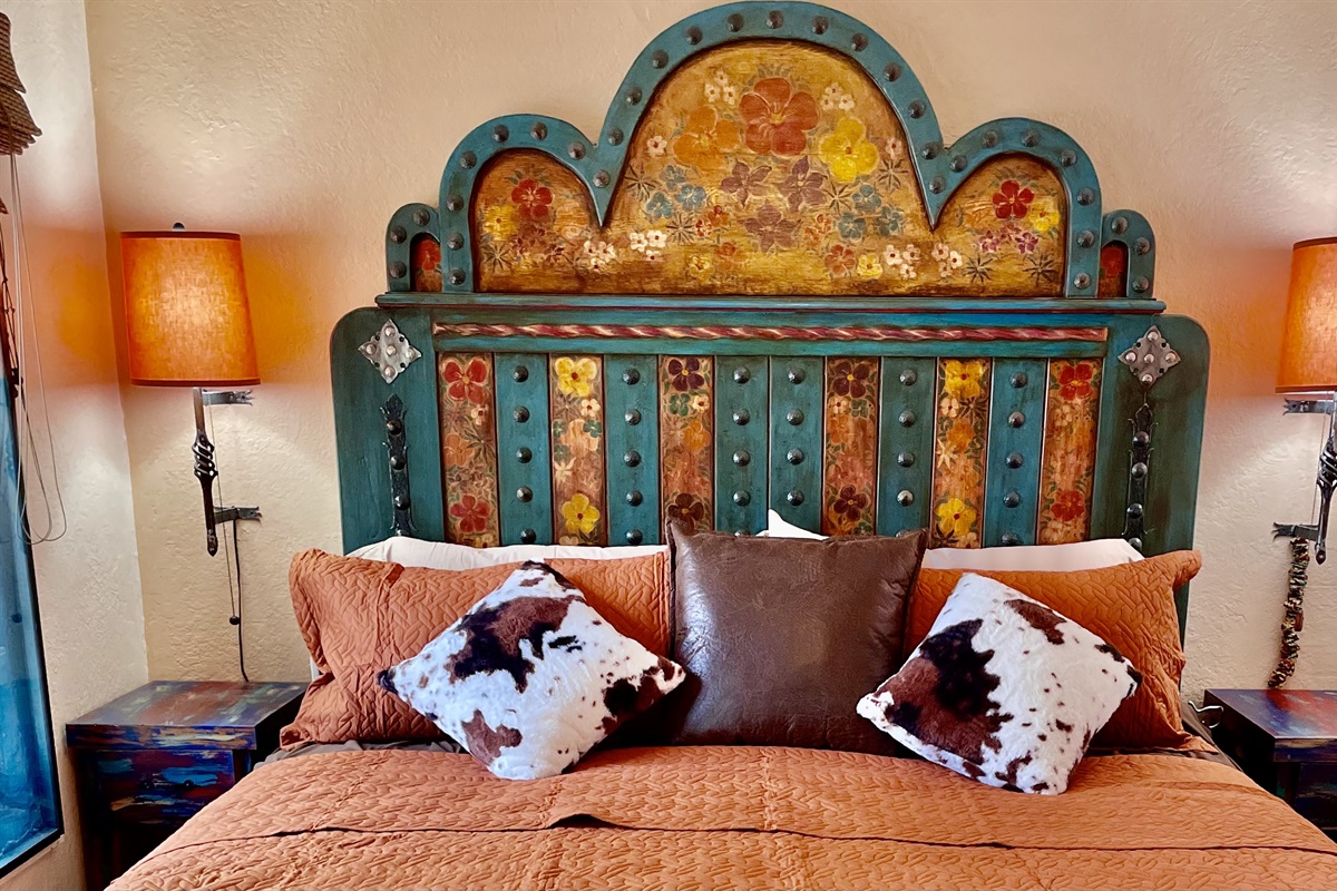 King-size bed with vibrant textiles and artistic accents.