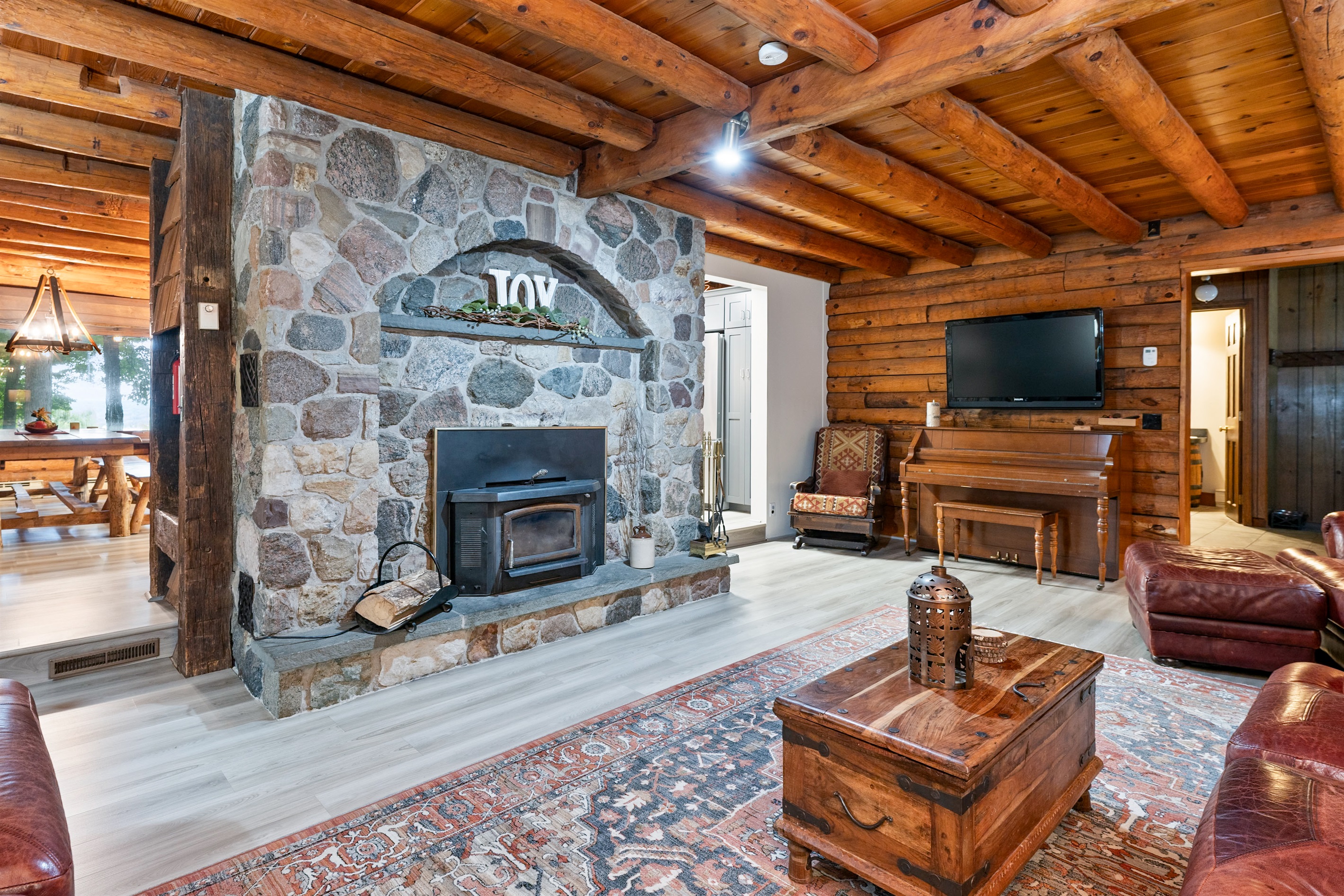 Rustic charm meets comfort with a stunning stone fireplace, warm wood interiors, and inviting leather couches, creating the ultimate cabin retreat atmosphere.
