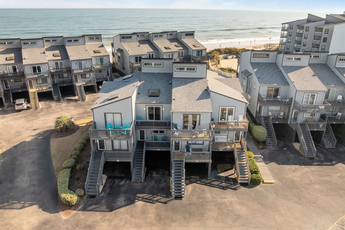 Drone view showing Shipwatch II&rsquo;s prime location along New River Inlet Rd, with the Atlantic Ocean and beach access just beyond the neighboring homes