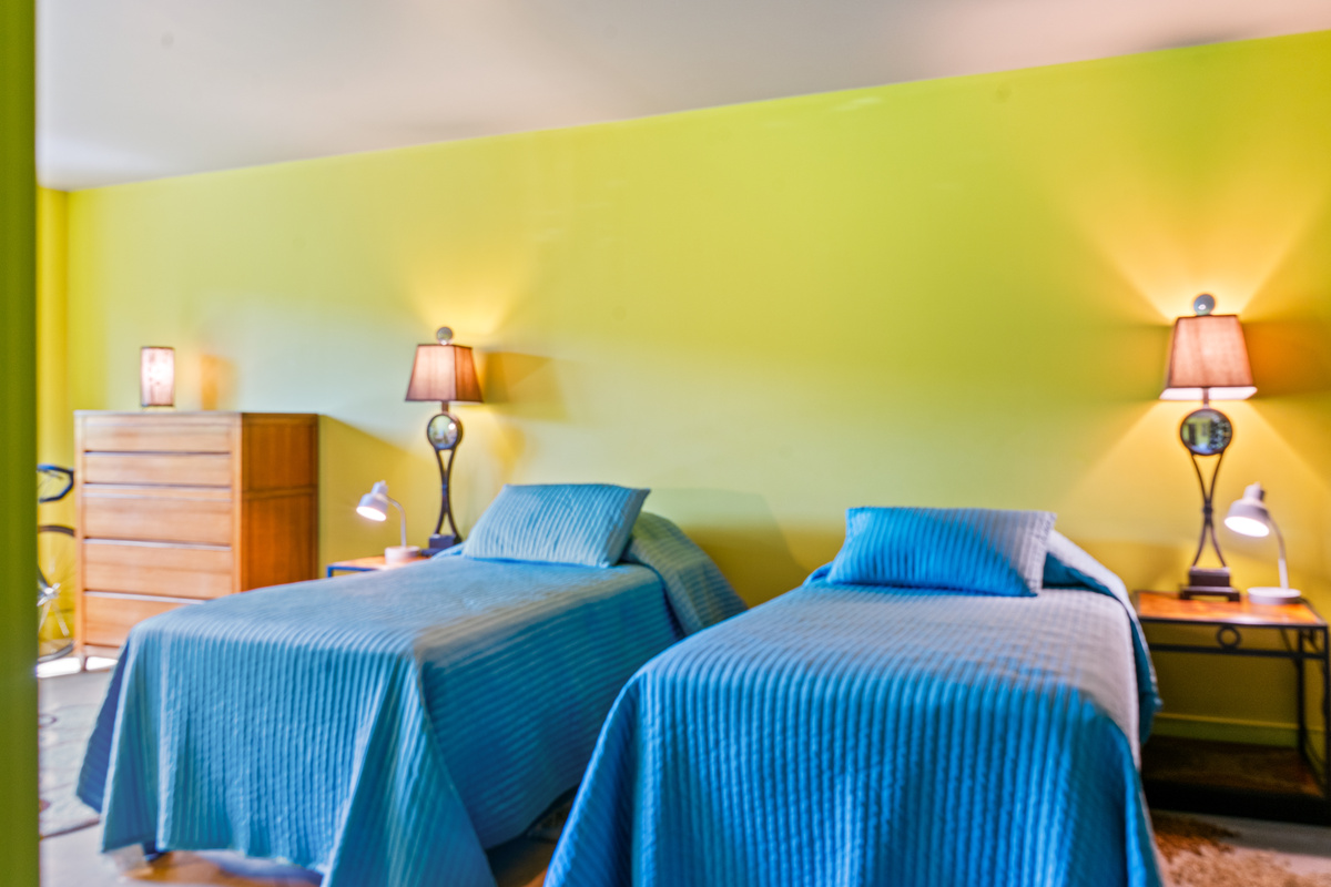 Flexible sleeping arrangements at "The Crag." The Base Camp bedroom offers dual twin beds, individual reading lamps, side tables, and ample dresser storage—designed for maximum comfort and privacy on the lower level near Acadia.
