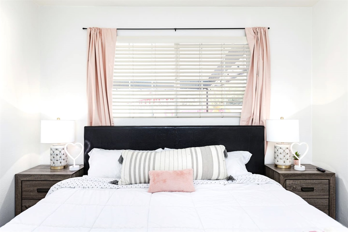 Enjoy restful nights on a plush bed with coordinated linens, pink curtains, and matching bedside lamps.

