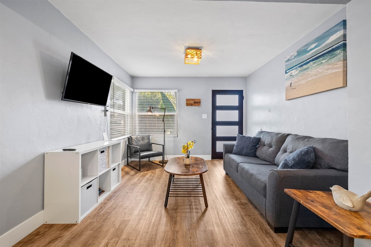Step into our aesthetic living room, featuring a stylish sofa, cute coffee table, and vibrant painting. Relax with a TV and a cozy chair illuminated by soft light, creating the perfect space for comfort and relaxation during your stay!