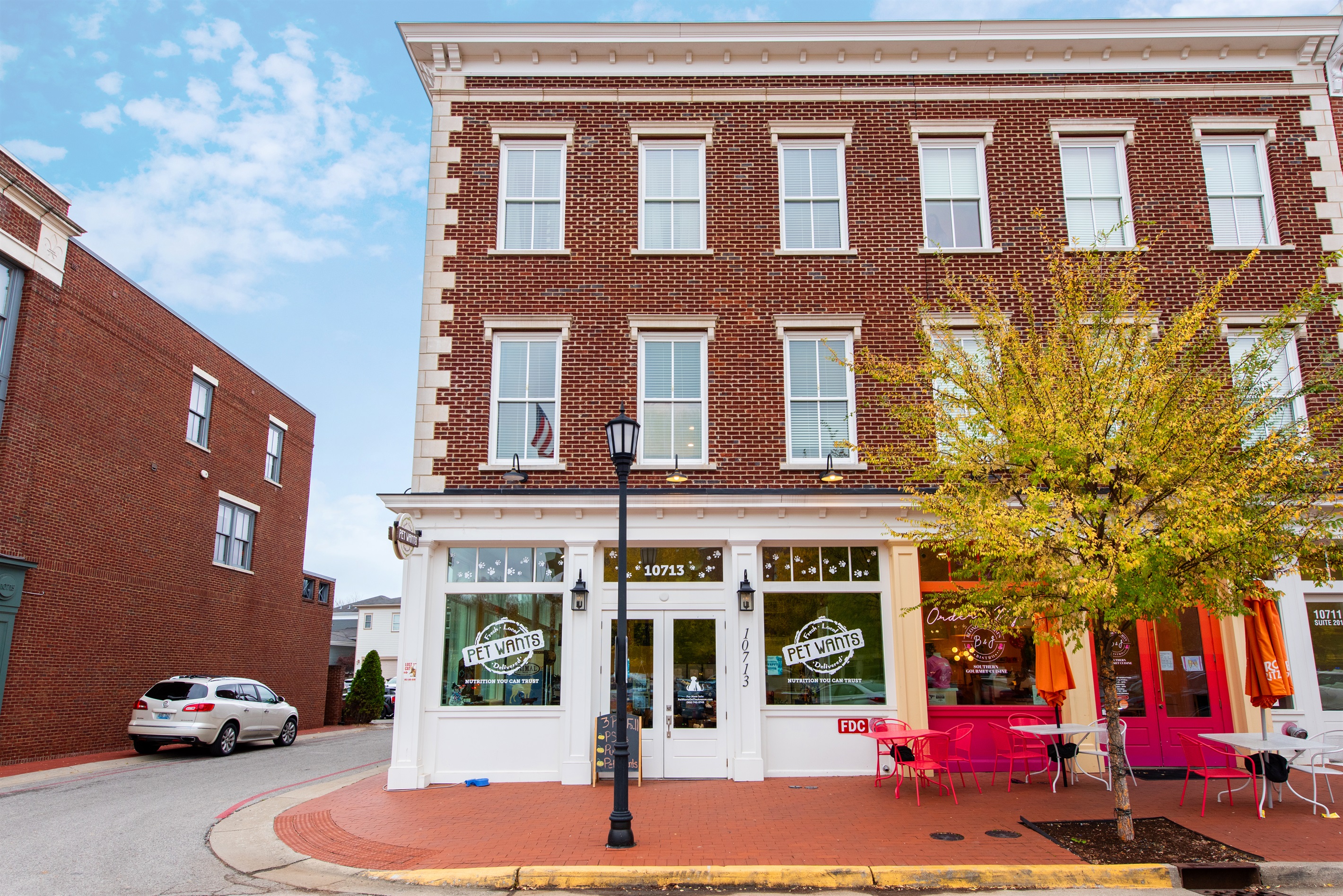This photo highlights the vibrant storefronts at the base of your stay in Norton Commons, featuring charming red brick architecture and local businesses that invite exploration just steps from your door.