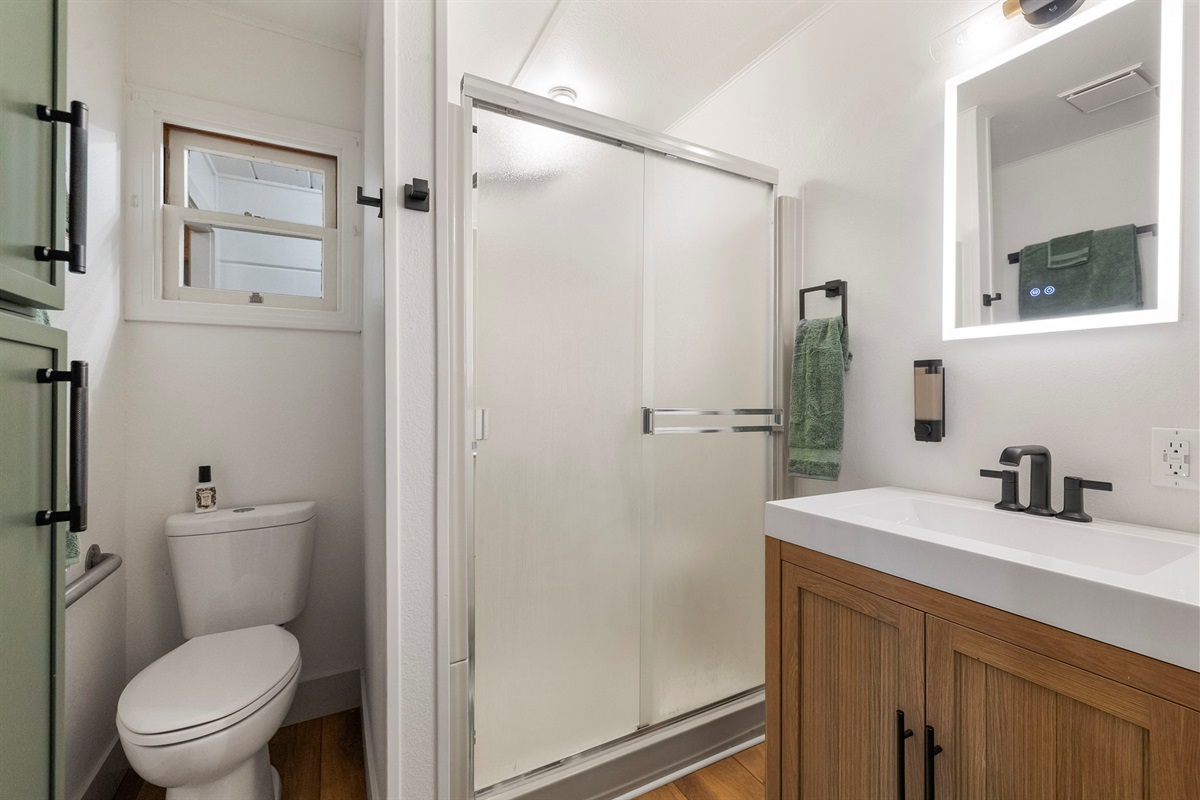 Updated master bathroom with storage for towels, shower with rainhead shower head, led mirror and bathroom supplies.