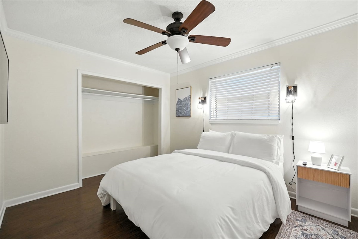 guest bedroom with queen bed, reading lamps, and 50" smart tv