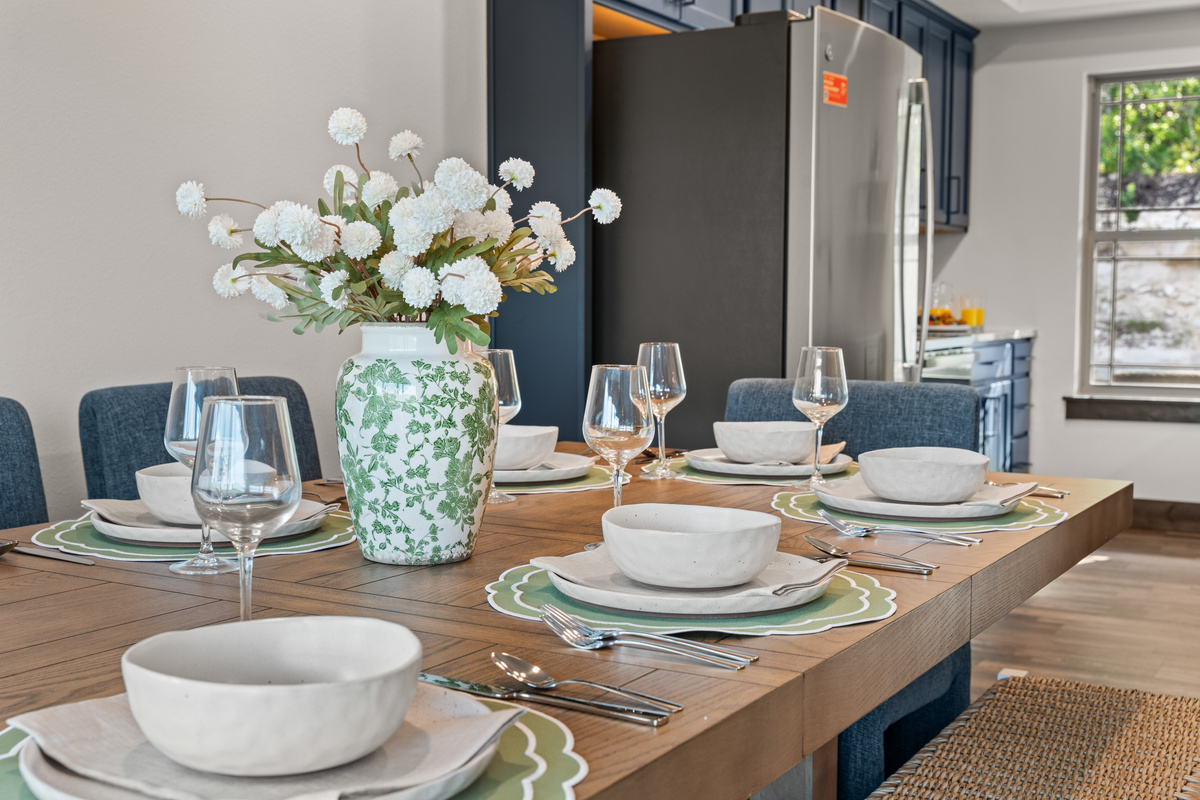 The dining table is set with scalloped placemats, stoneware, and wine glasses for the whole group.