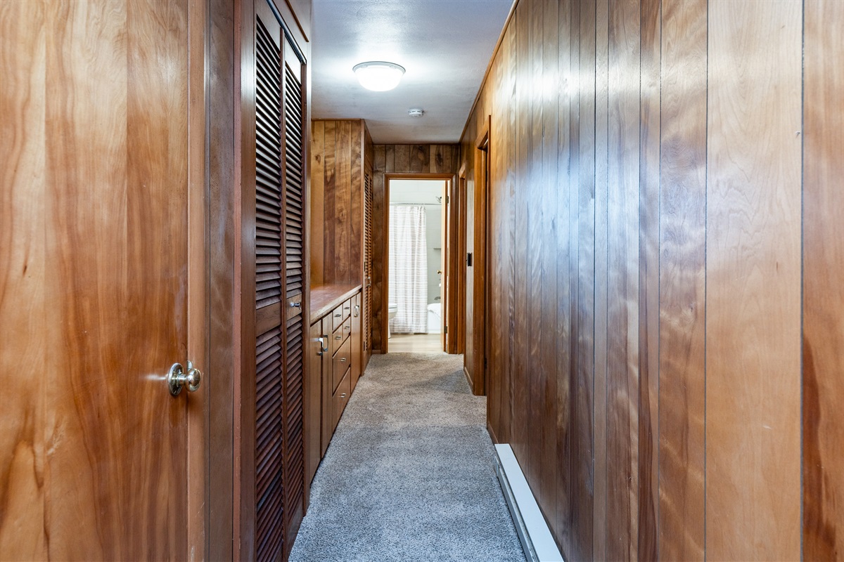 Warm wood-paneled hallway with built-in storage and direct access to the bathroom for added convenience.