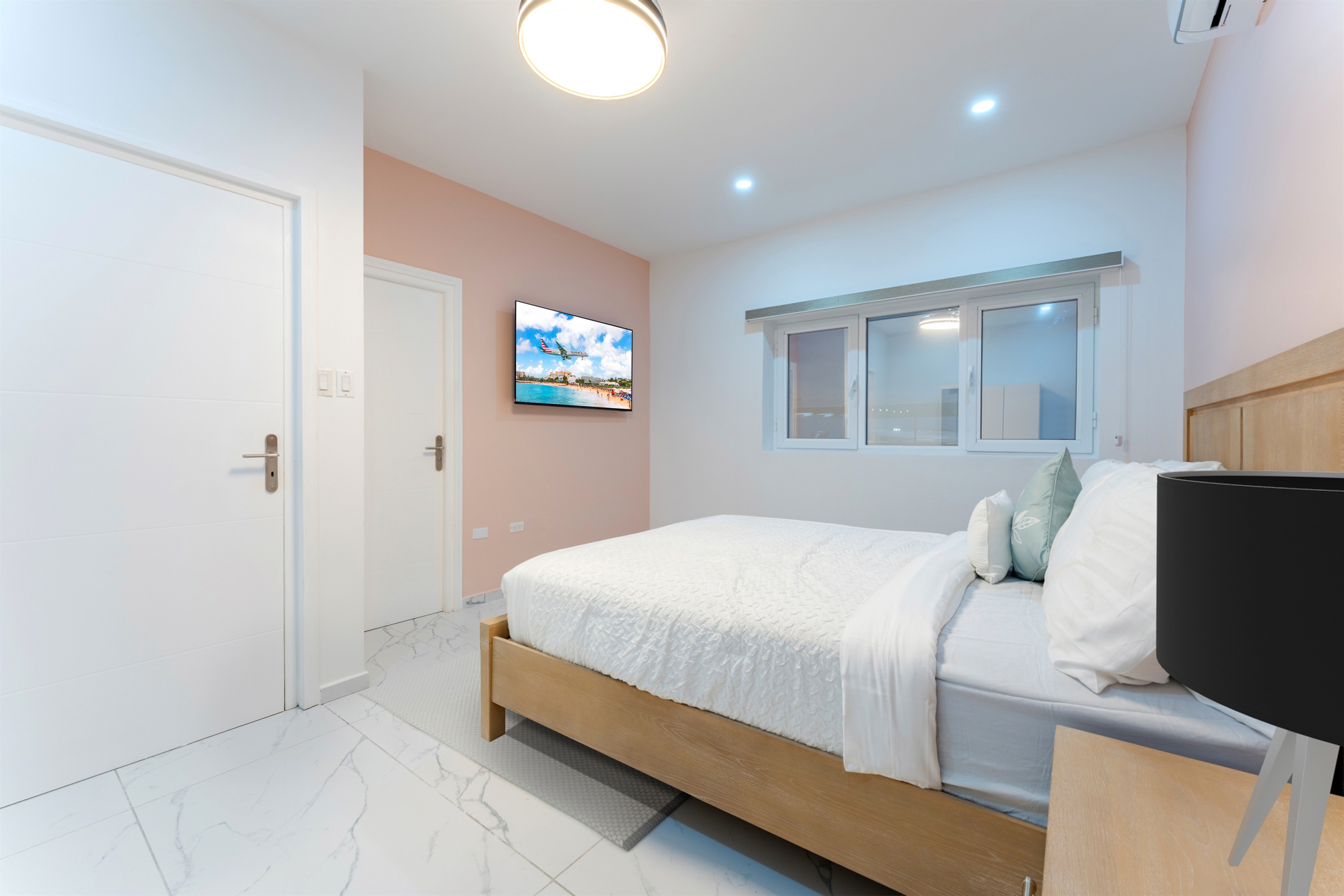 Alternate angle of the queen bedroom showing accent wall, bedside tables and smart TV