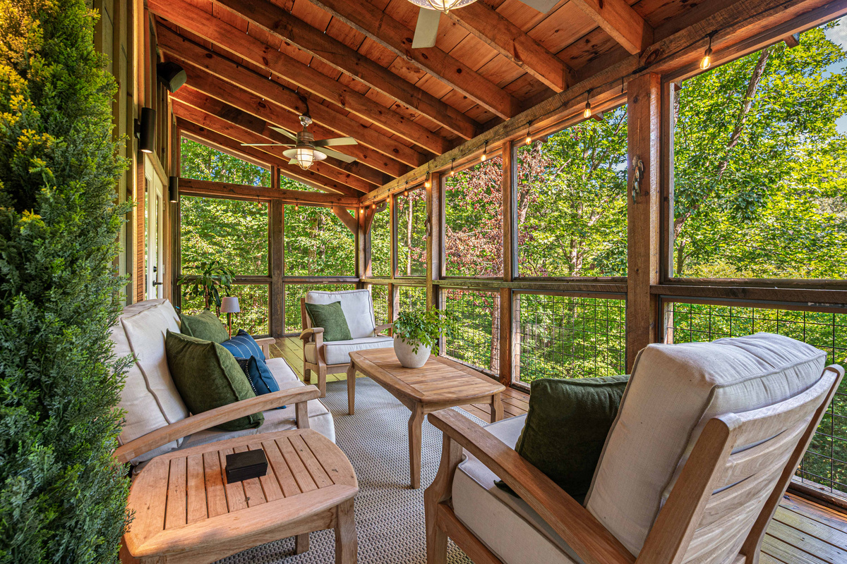 Upper screened-in deck with comfortable lounge seating for relaxing and unwinding.