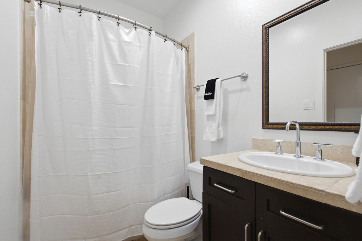 Full bathroom with walk-in shower, dark wood vanity, and classic fixtures. Stocked with Ginger Lily Farms bath essentials. Clean, functional, and ready for your arrival.