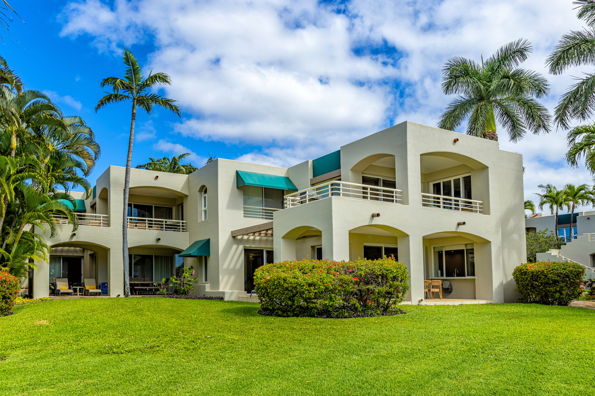 Your ground-floor condo is partially concealed behind the bougainvillea hedge. The turquoise awning center-left is your bedroom window, the wrap-around lanai to the right of the awning. This is a four-plex.