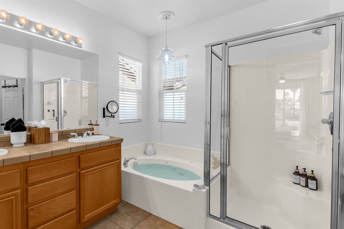 Luxurious en suite bathroom with soaking tub, glass shower, and dual vanities