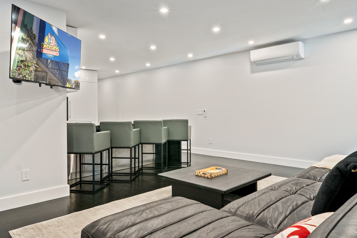 View from the guest bedroom into the open-concept hub. Stream favorite shows on the 55-inch Roku smart TV while relaxing on the sectional or sitting at the kitchen island. Fully climate-controlled in the heart of downtown Bar Harbor.