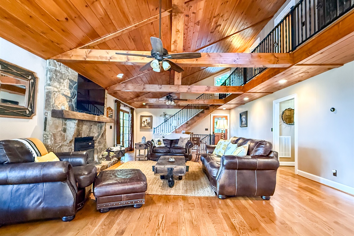 The large, spacious living room features vaulted ceilings, plenty of comfortable seating with couches and chairs, and a smart TV for your entertainment
