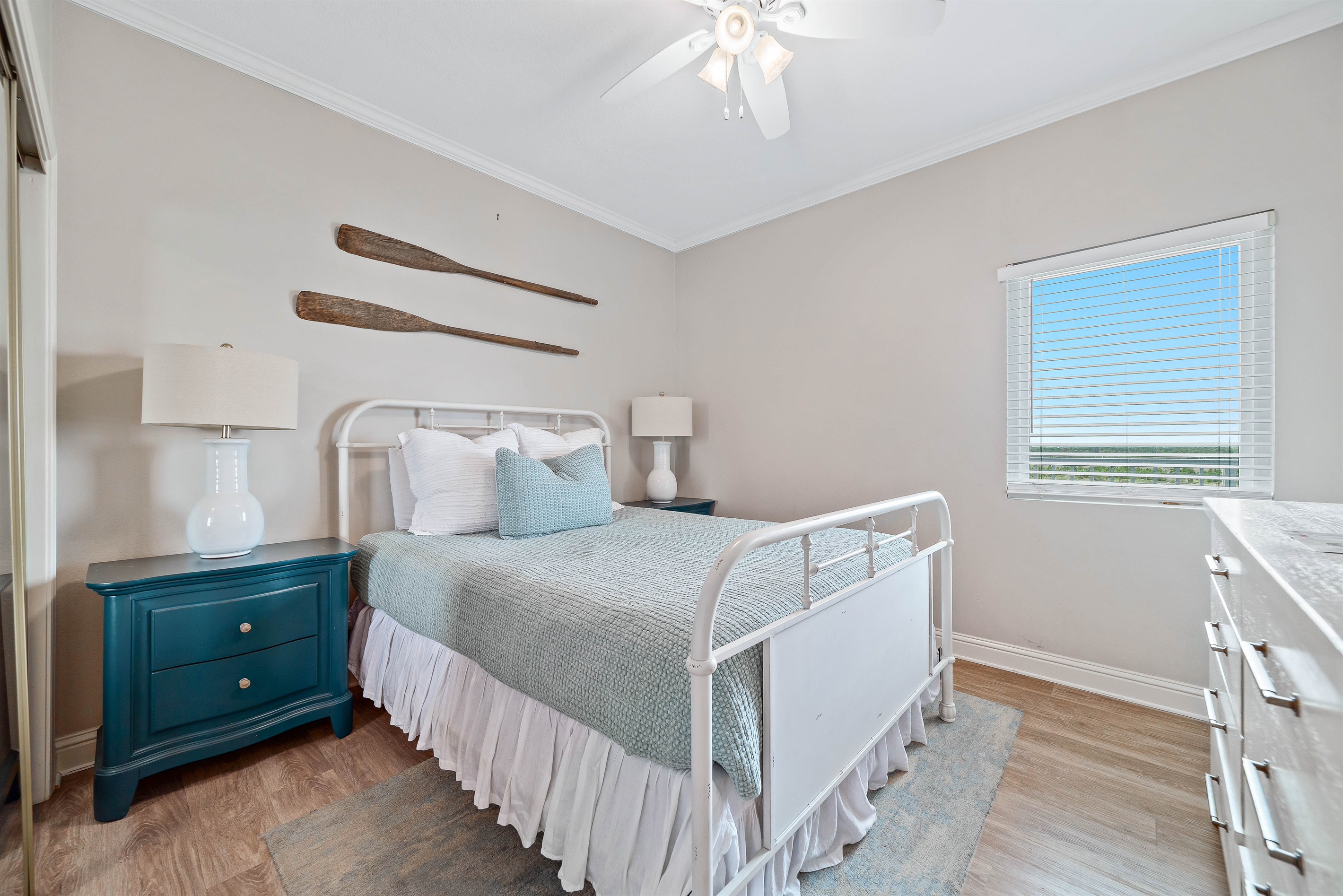 This charming guest bedroom offers a comfortable queen-sized bed with vibrant linens, complemented by practical storage solutions. A delightful space to unwind.