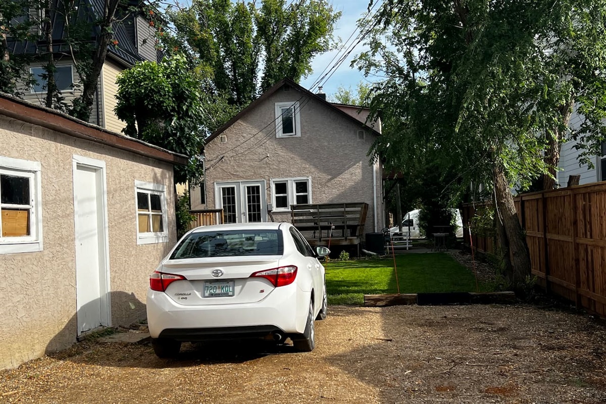 View of the back yard greenspace with elm trees and a place to park your vehicle. 