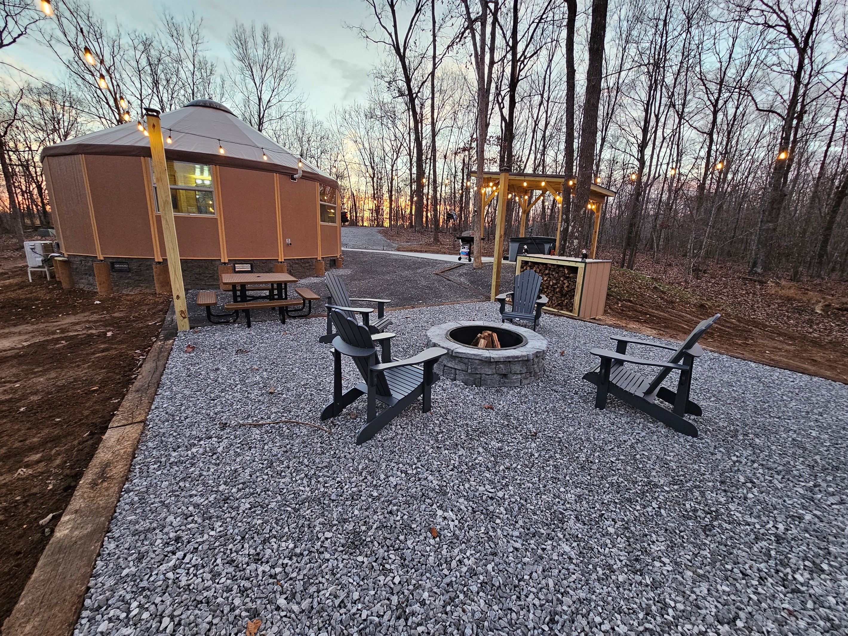 As the sun sets, Eagle Retreat glows with warm lights, a crackling fire pit, and a private hot tub pavilion—an intimate forest retreat designed for romance, relaxation, and unforgettable eveni