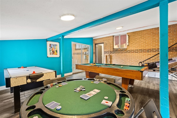 A well-appointed room featuring a poker table, pool table, and table hockey for a variety of engaging and competitive entertainment options
