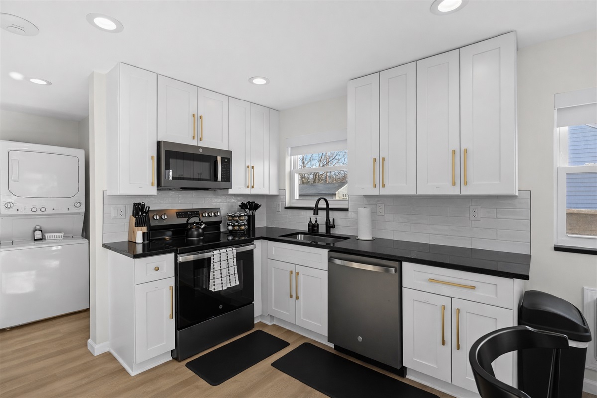 Bright, modern kitchen with crisp white cabinetry, sleek appliances, and in-unit laundry—designed for effortless cooking, convenience, and comfort.