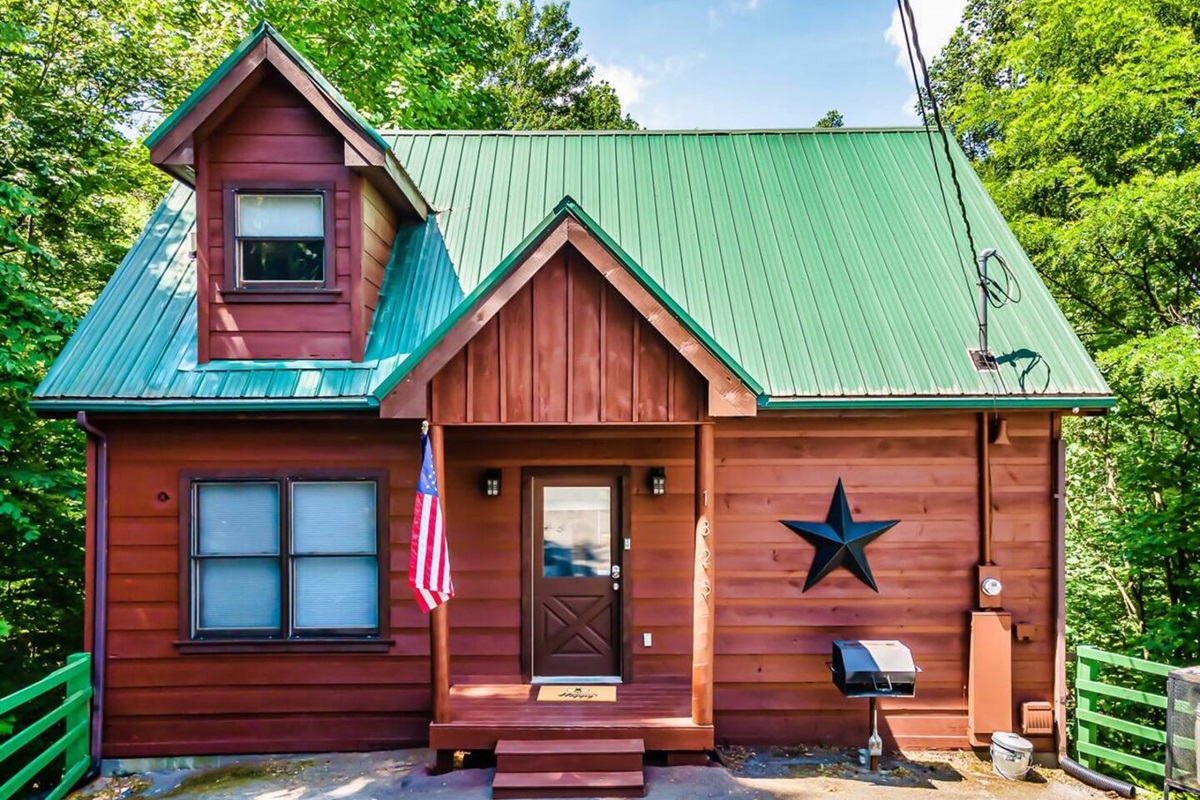 A picturesque mountain cabin with a green roof surrounded by lush greenery, offering a tranquil retreat