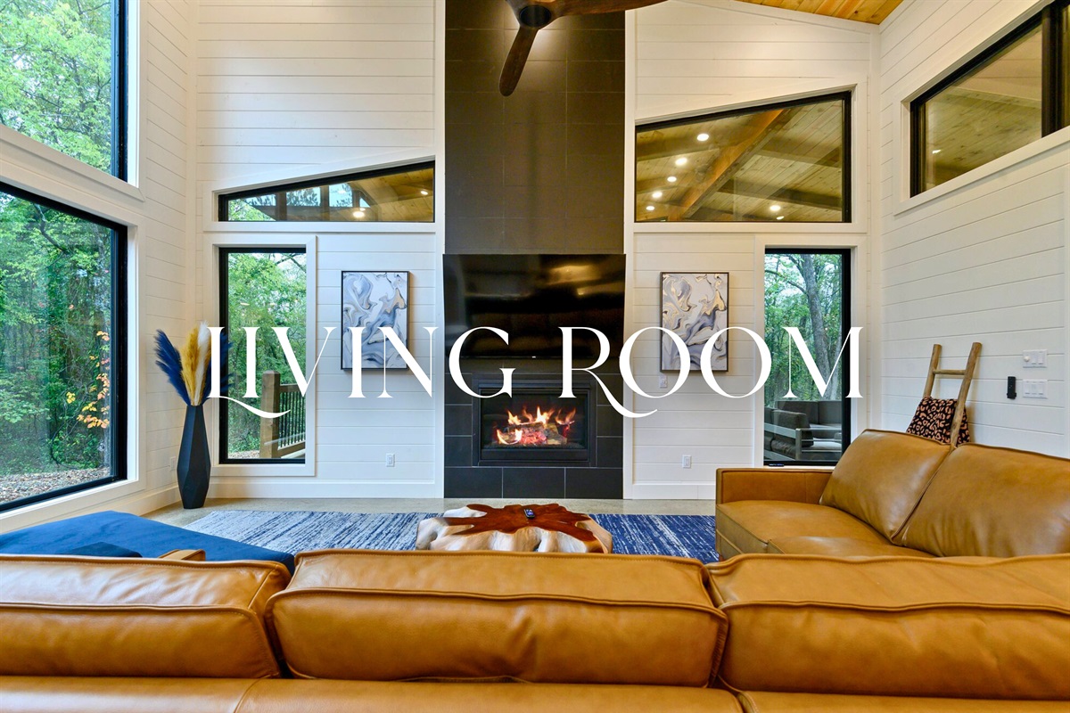 A relaxed living room with warm leather seating, a feature fireplace, and large windows for that perfect mix of cozy and modern.