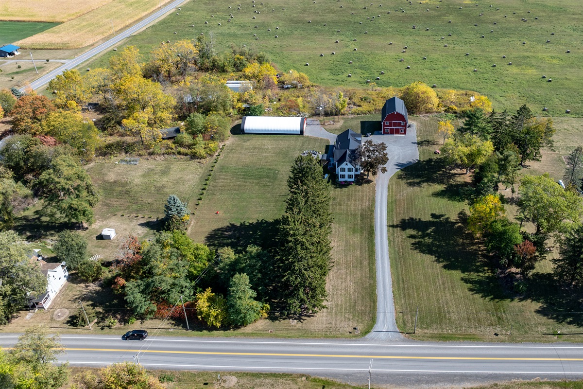 Aerial perspective of the property’s long driveway, lush trees, and inviting open layout