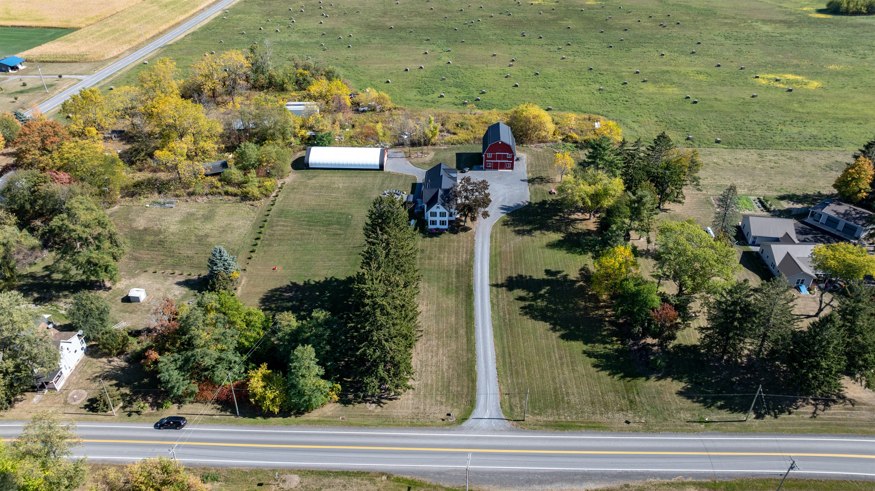 Aerial perspective of the property’s long driveway, lush trees, and inviting open layout