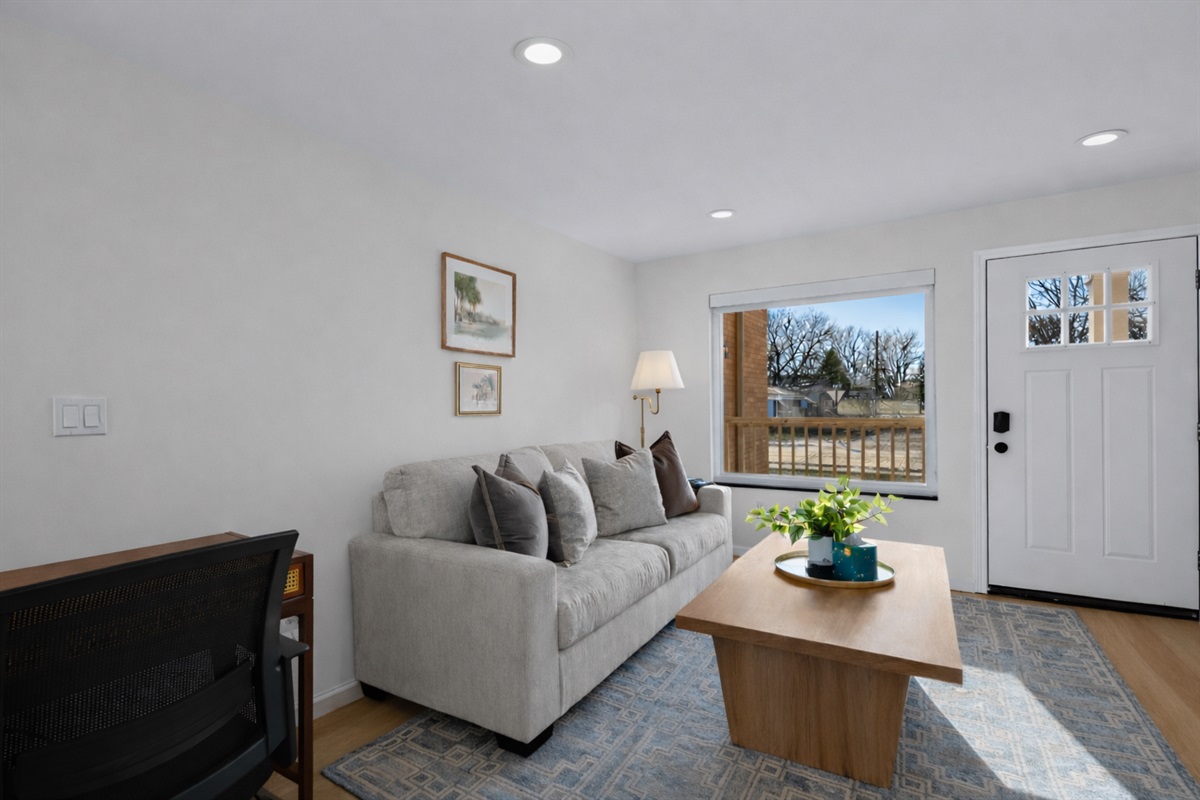 Bright, modern living room with plush seating, clean lines, and a large window that fills the space with natural light and a warm, welcoming feel.