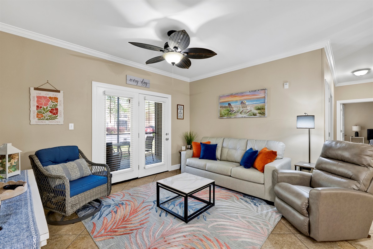 Living room with leather sleeper sofa, recliner, arm chair, ceiling fan and wall mounted smart TV 