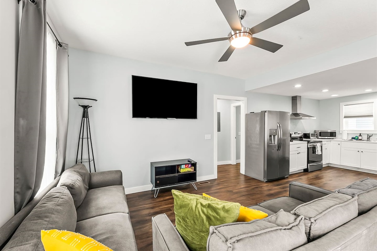 Comfort meets convenience in this inviting living room with a large TV, board games, and easy access to the kitchen and dining area.