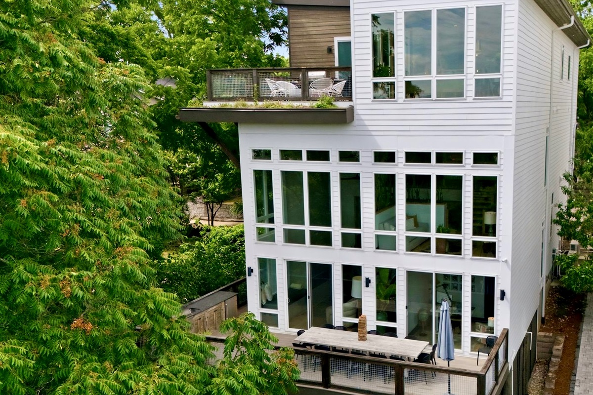 Striking multi-story exterior w/ walls of glass & a verdant rooftop garden above the treetops.

