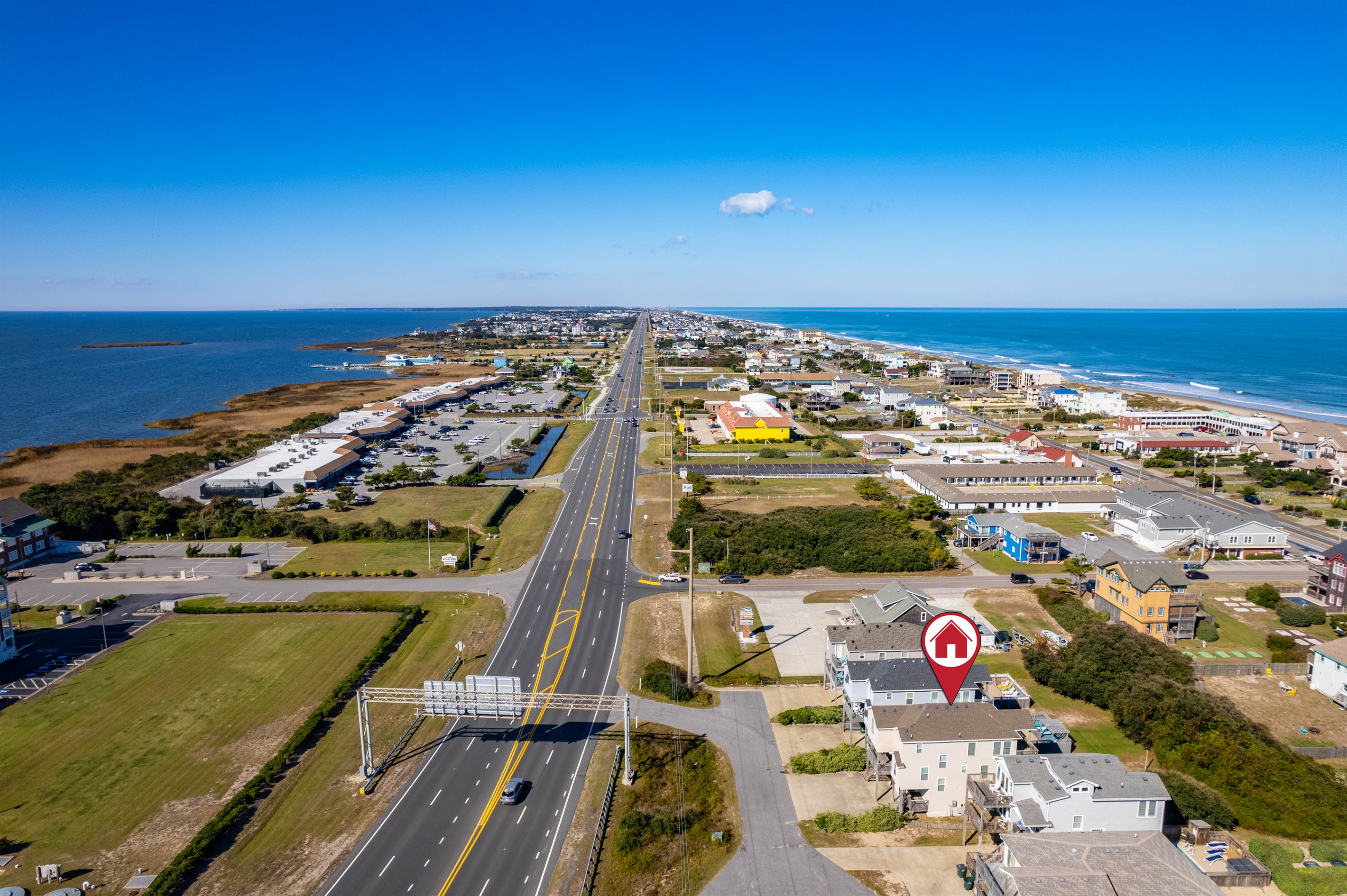Drone view looking down the main beach road, highlighting the home’s convenient location within a well-connected Outer Banks community.