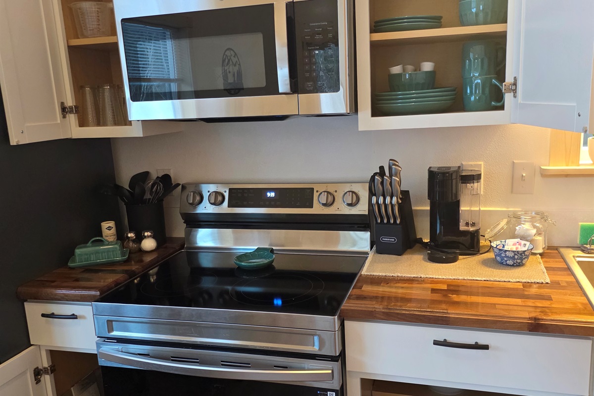 Fully stocked kitchen includes an electric range, microwave, refrigerator, and Keurig.