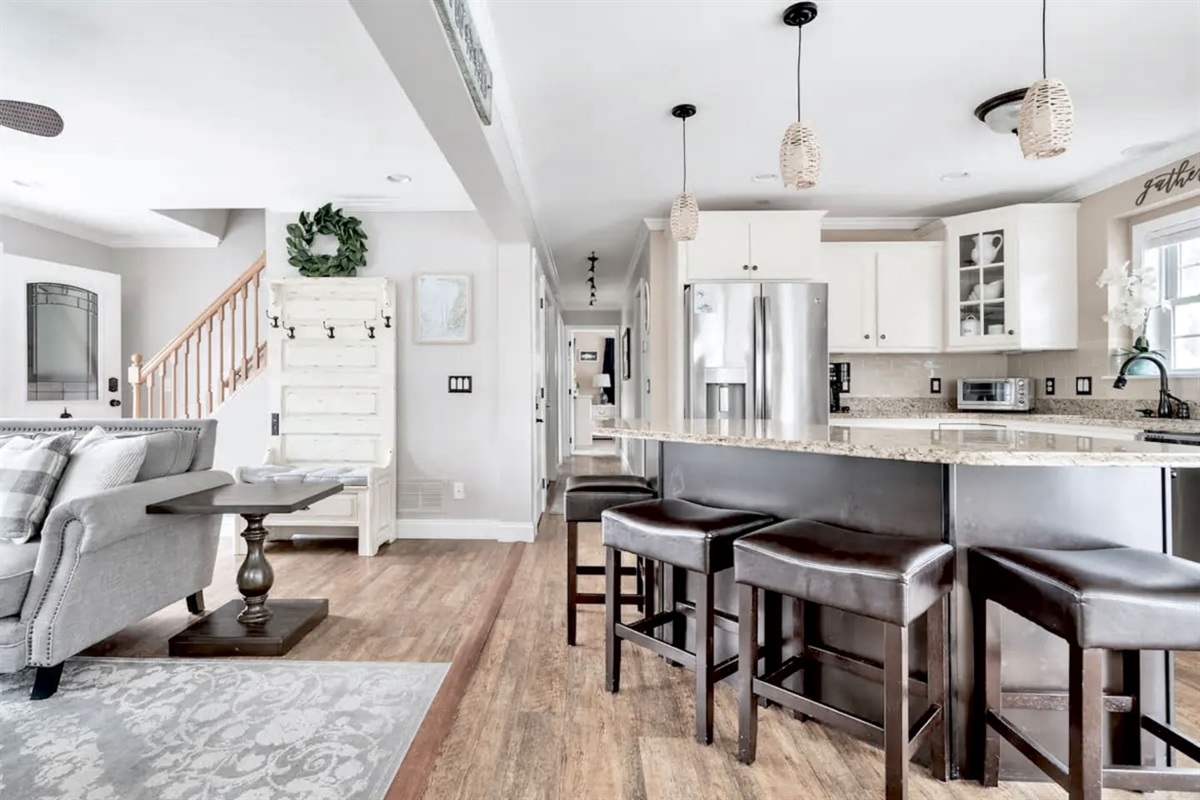 This bright, open-concept layout seamlessly connects the kitchen and living area. Enjoy casual dining at the granite island with barstool seating, or relax on the plush sectional in the adjacent living room.