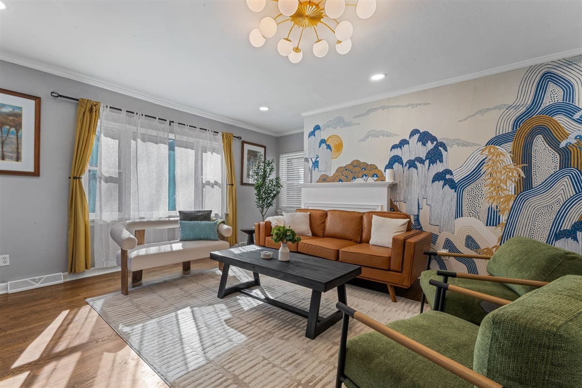 Design-forward living room with a beautiful mural, plush seating, and tons of natural light — a relaxing retreat after exploring Knoxville