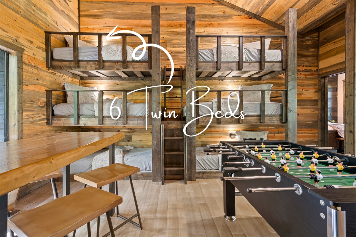 A cluster of four bunk beds, set against a wood-plank wall, provides a comfortable sleeping space for multiple guests.