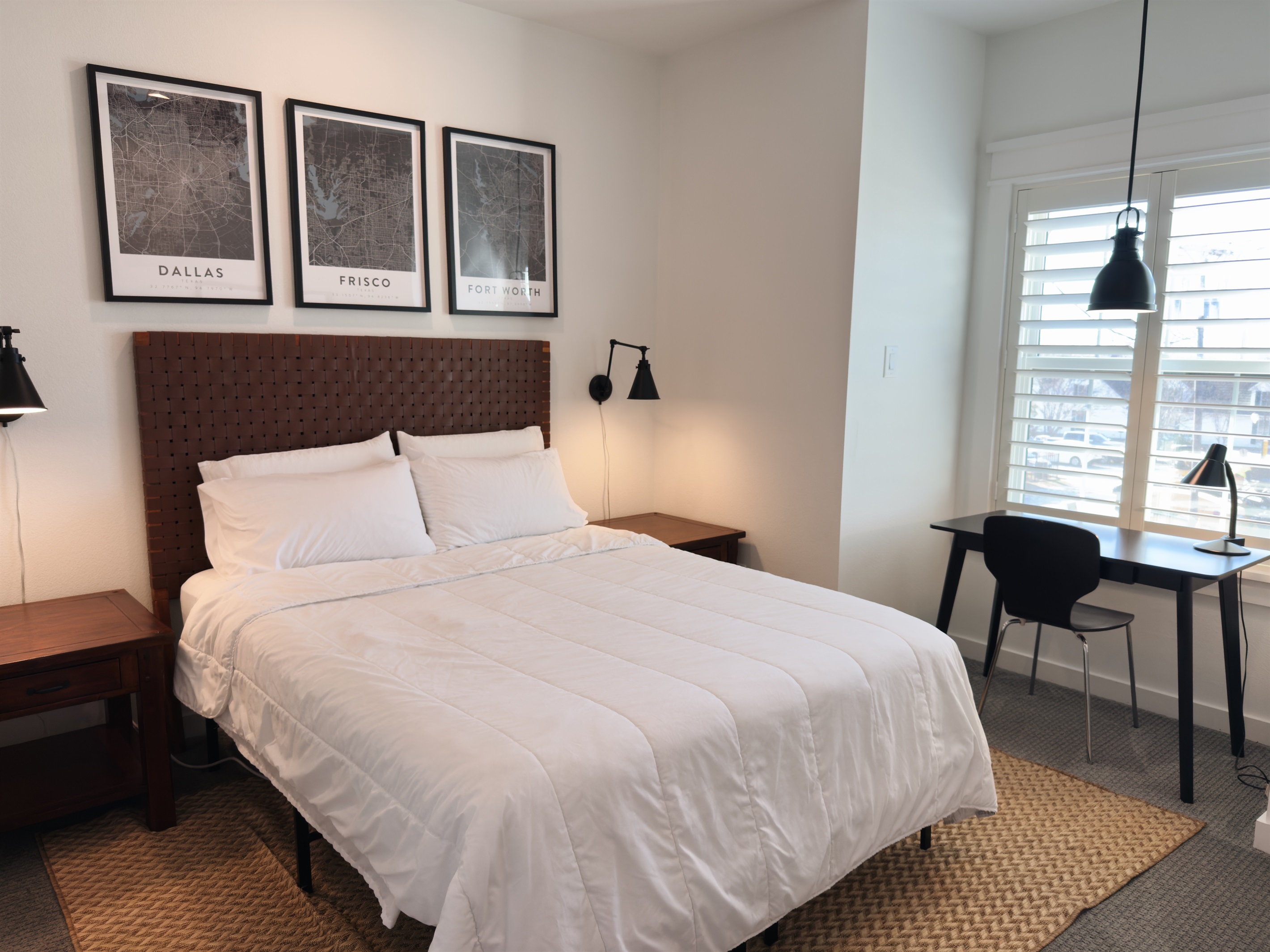 Bright and inviting bedroom with a comfortable bed, reading lamps, and space to relax or work.