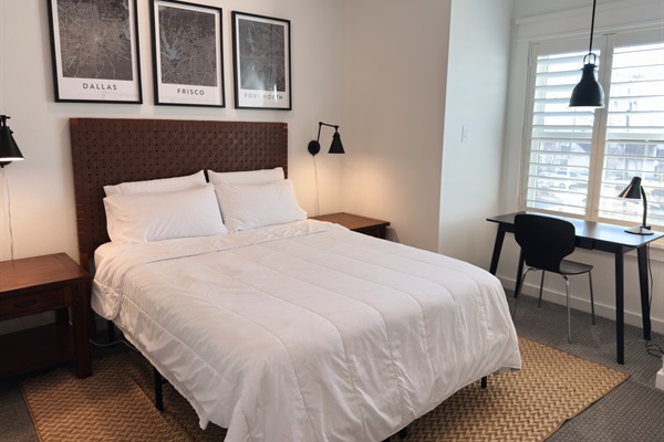 Bright and inviting bedroom with a comfortable bed, reading lamps, and space to relax or work.