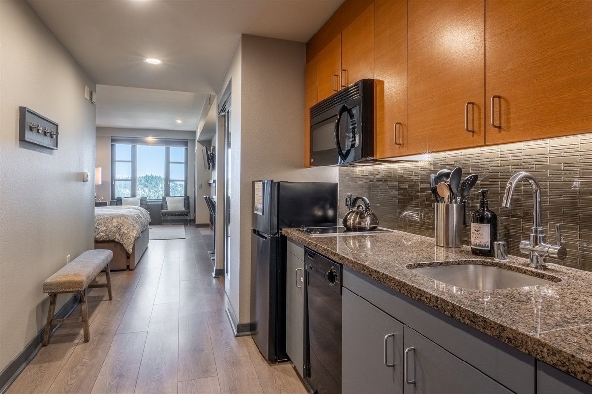 From the front door, the galley kitchen opens into the sleeping and living areas beyond, all warmed by natural light from the expansive windows.